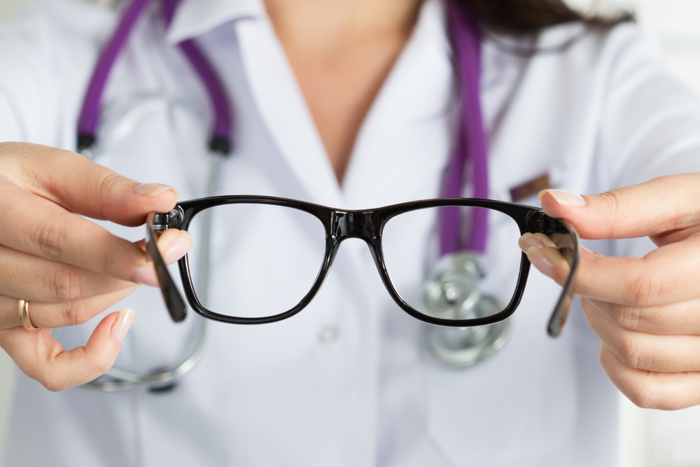 Female,Oculist,Doctor,Hands,Giving,Pair,Of,Black,Glasses,To